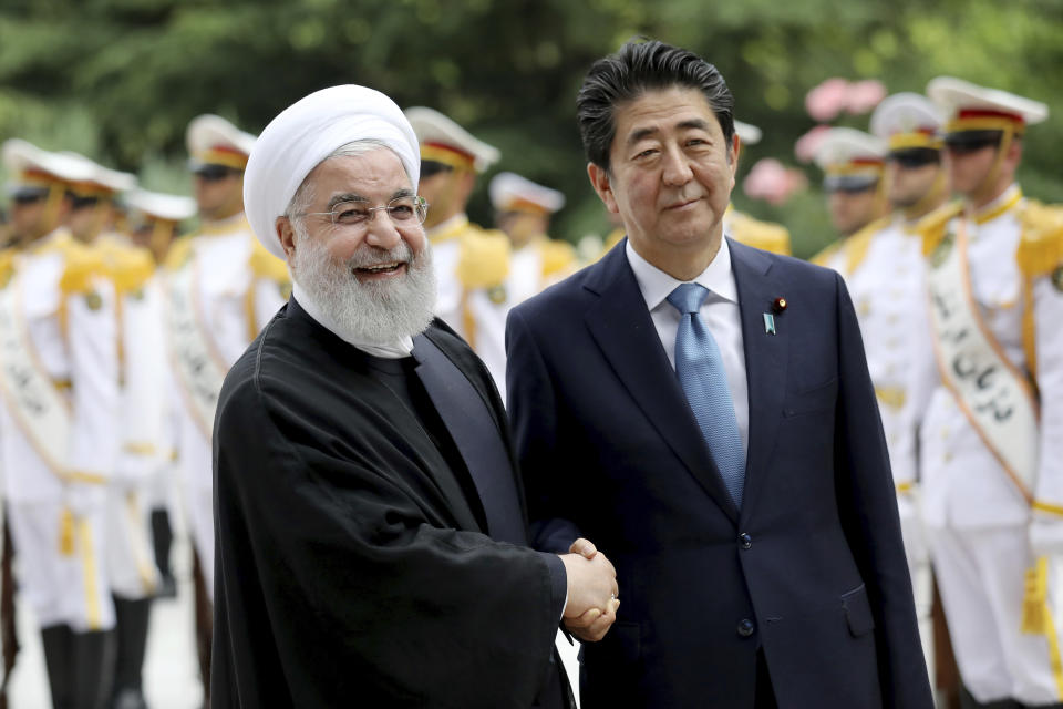 Japanese Prime Minister Shinzo Abe, right, shakes hands for the cameras with Iranian President Hassan Rouhani, during the official arrival ceremony, at the Saadabad Palace in Tehran, Iran, Wednesday, June 12, 2019. (AP Photo/Ebrahim Noroozi)