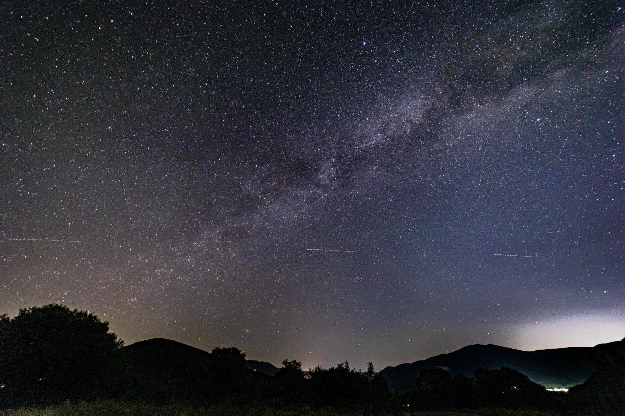 Milky Way captured with long exposure photography technique. Milkyway is the visible part of our galaxy seen during the dark night from the mountain area near Xanthi city in Northern Greece. Night landscape over the mountain with colourful Milky Way sky dome, the cloudless sky at mountains with the starry sky with hills at summer with the beautiful Universe and Space background. The Milky Way is a barred spiral galaxy the galaxy that includes the Solar System, with the name describing the galaxy appearance from Earth, a hazy band of light seen in the night sky formed from stars. The lines appearing are aircraft passing, satellite and meteorites while the lower light pollution comes from the city lights. Xanthi, Thrace, Greece on July 2024 (Photo by Nicolas Economou/NurPhoto via Getty Images)