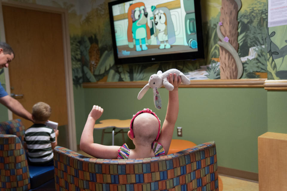 Callie Weatherford holds her stuffed bunny, Lamby, as she watches television in a waiting room at Children's National on June 30. "I don't think she completely understands what she's up against," says her mother, Stephanie Weatherford, of Callie's DIPG diagnosis. (Washington Post photo by Minh Connors)