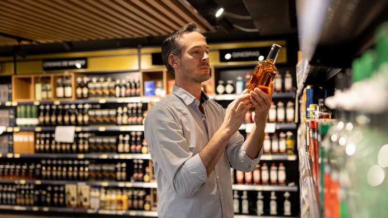 man inspecting liquor at store