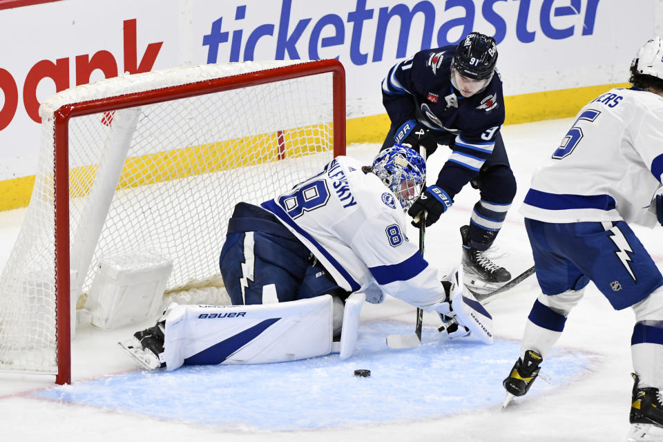 Tampa Bay Lightning goaltender Andrei Vasilevskiy (88) makes a save on Winnipeg Jets' Cole Perfetti (91) during the third period of an NHL hockey game Tuesday, Jan. 2, 2024, in Winnipeg, Manitoba. (Fred Greenslade/The Canadian Press via AP)
