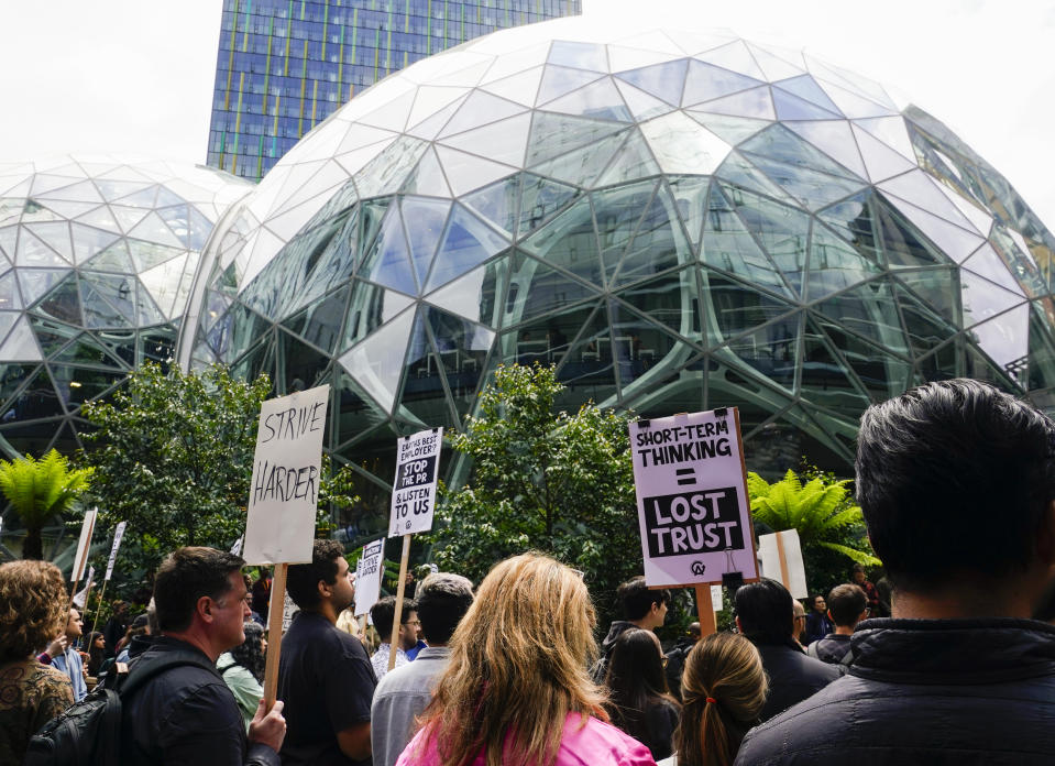 Amazon corporate workers hold picket signs in front of the Amazon Spheres while participating in a walkout to protest the company's return-to-office policies, Wednesday, May 31, 2023, in Seattle. Organizers called attention to the climate impact of commutes, saying it runs counter to the company's "Climate Pledge" to be carbon neutral by the year 2040, as well as concerns about recent layoffs. (AP Photo/Lindsey Wasson)