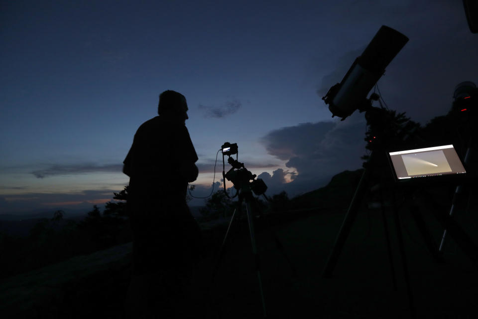 As the sun sets at Grandfather Mountain astrophotographer Johnny Horne makes exposures of the evening sky as he waits for Comet NEOWISE to appear from behind storm clouds Friday, July 17, 2020 in Linville, N.C. (AP Photo/Gerry Broome)