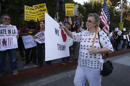 A Trump supporter walks past protesters outside the Luxe Hotel, where Republican presidential candidate Donald Trump was expected to speak in Brentwood, Los Angeles, California, United States July 10, 2015. REUTERS/Lucy Nicholson