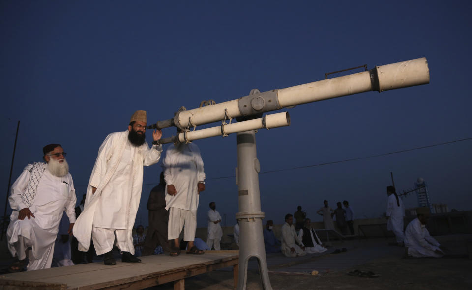 Clerics of Pakistan's Moon Sighting Committee search the sky with a telescope for the new moon that signals the start of the Muslim fasting month of Ramadan, in Karachi, Thursday, April 23, 2020. (AP Photo/Fareed Khan)