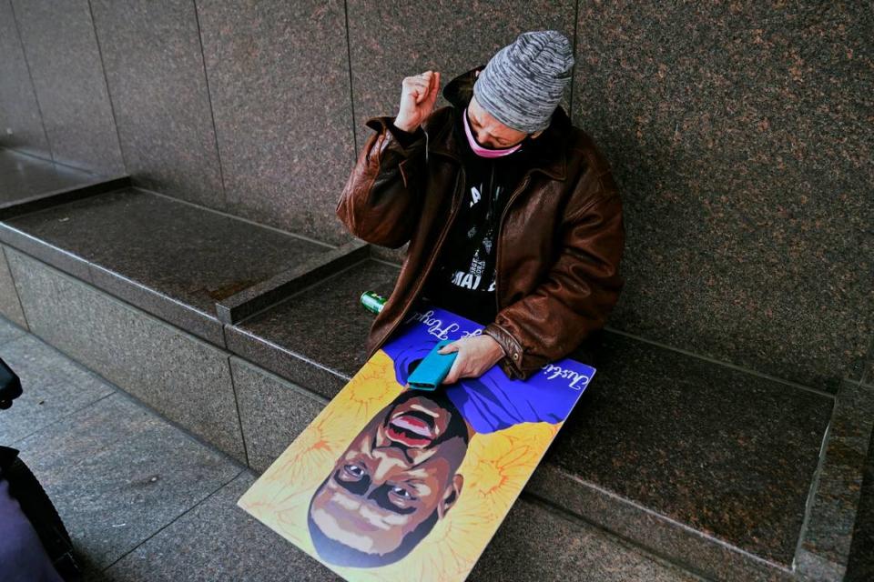 A woman holding a George Floyd poster pumps her fist across the street from the Hennepin County Government Center in Minneapolis on Tuesday after jurors found former police Officer Derek Chauvin guilty on all counts of murder and manslaughter in Floyd’s death last May.