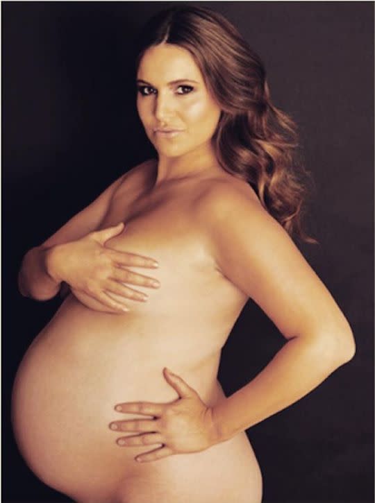 a pregnant woman and a man topless in pajama Pants in the kitchen