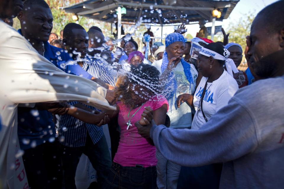 In this Feb. 8, 2014 photo, Rev. Jules Campion douses a Christian pilgrim in holy water to expel a malevolent spirit during a gathering organized by Our Lady of Fatima Bible Center in the village of Bois-Neuf, Haiti. Although the center is Roman Catholic, the three-day event had an evangelical feel, and some elements of Voodoo. (AP Photo/Dieu Nalio Chery)