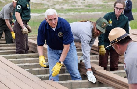 U.S. Vice President Mike Pence helps National Park Service workers lay planks along a boardwalk near Old Faithful Geyser in Yellowstone National Park