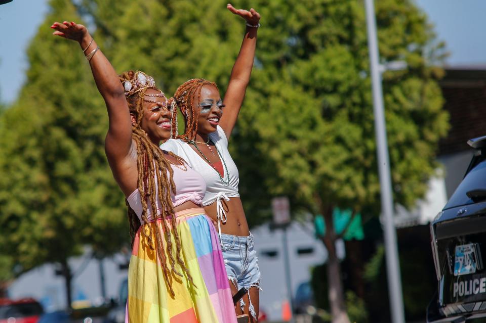 Crystal (Was) Wallar and Madison Jackson wave at the groups walking through the second annual Pride Alliance downtown Pride Parade near Scissortail Park.