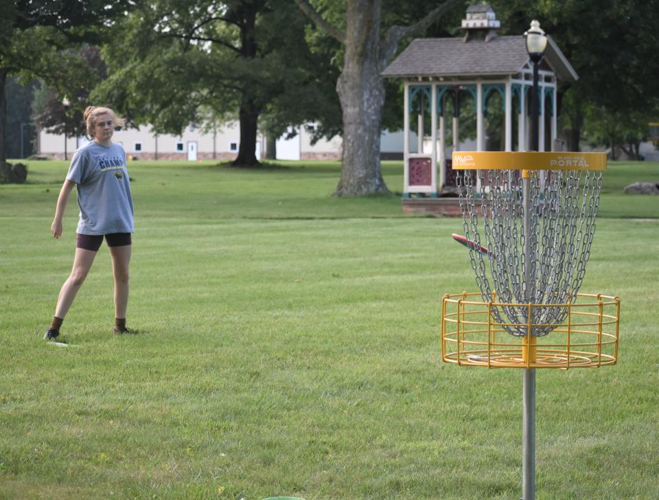 Dani Hohlbein watches her throw land in a basket Thursday at the disc golf course in place on the PlaneWave Instruments campus in Adrian.