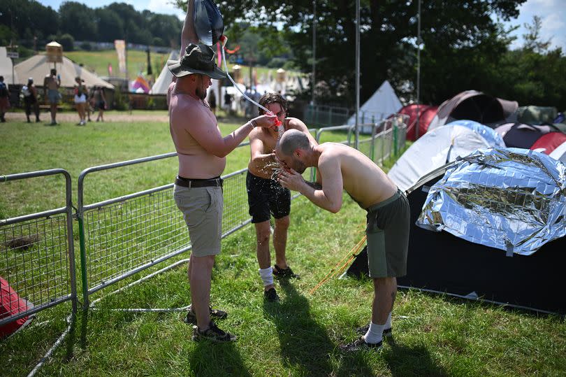 Festivalgoers cool down with a home-made shower on the opening day of the Glastonbury festival at Worthy Farm in the village of Pilton in Somerset, southwest England, on June 26, 2024. The festival takes place from June 26 to June 30. (Photo by Oli SCARFF / AFP) (Photo by OLI SCARFF/AFP via Getty Images)