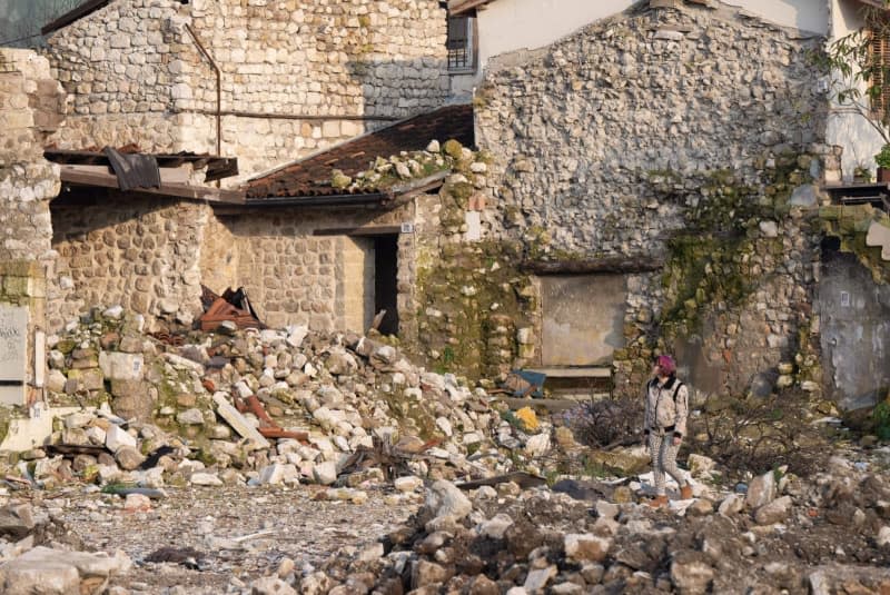 A woman walks past destroyed houses in the old town of Antakya. Numerous houses in the city center were destroyed or severely damaged in the earthquake a year ago. Boris Roessler/dpa