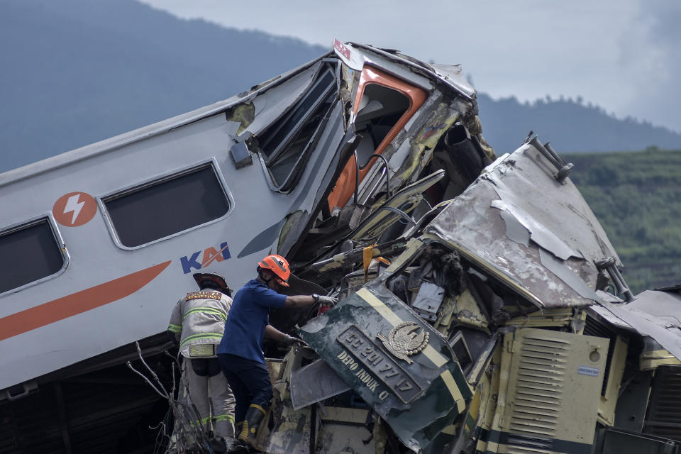 Rescuers inspect the wreckage after the collision between two trains in Cicalengka, West Java, Indonesia, Friday, Jan. 5, 2024. The trains collided on Indonesia's main island of Java on Friday, causing several carriages to buckle and overturn and killing at least a few people, officials said. (AP Photo/Abdan Syakura)