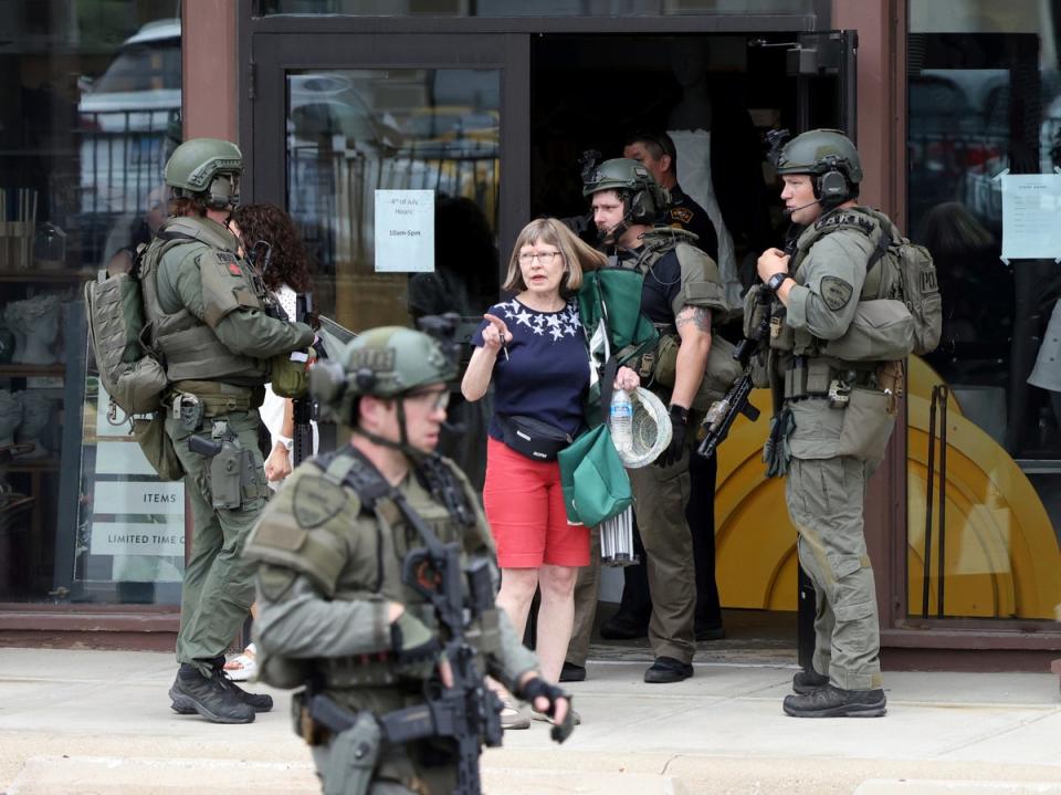 Law enforcement officers help evacuate people from a store in Highland Park (Brian Cassella/Chicago Tribune/AP)