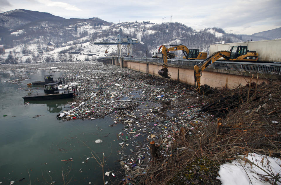 Huge cranes clear tons of garbage stuck at the foot of the hydro power plant at the Potpecko accumulation lake near Priboj, in southwest Serbia, Friday, Jan. 22, 2021. Serbia and other Balkan nations are virtually drowning in communal waste after decades of neglect and lack of efficient waste-management policies in the countries aspiring to join the European Union. (AP Photo/Darko Vojinovic)