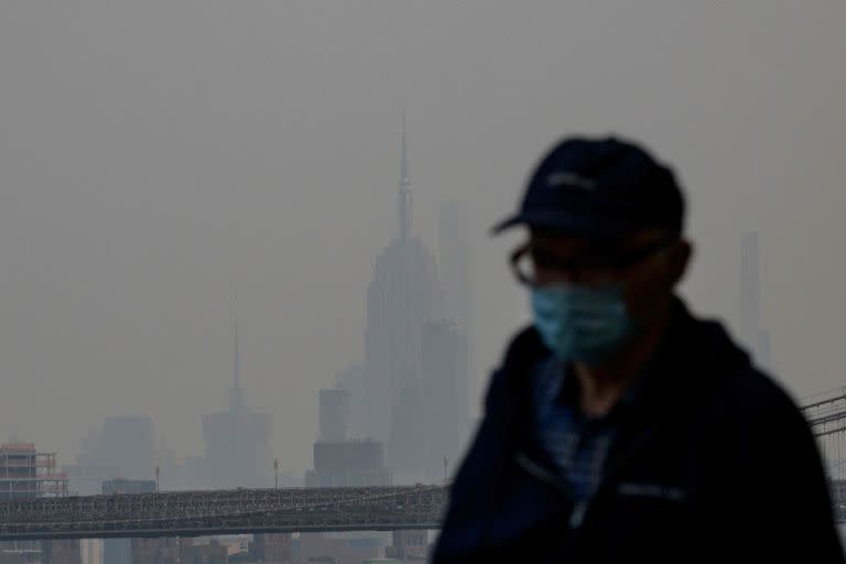 El Empire State Building se ve más allá de una persona que usa una máscara facial mientras el humo de los incendios forestales en Canadá causan condiciones brumosas en la ciudad de Nueva York 