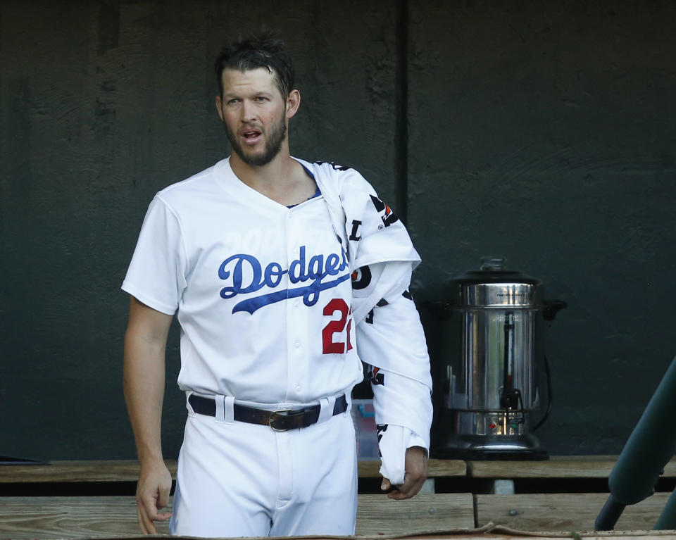 His arm wrapped in towels, Clayton Kershaw (22) watches from the dugout in the first inning of a Triple-A Oklahoma City Dodgers game against the San Antonio Missions Thursday, April 4, 2019, in Oklahoma City. Kershaw is pitching in a rehab assignment for Triple-A affiliate Oklahoma City. Catcher Will Smith is at right. (AP Photo/Sue Ogrocki)