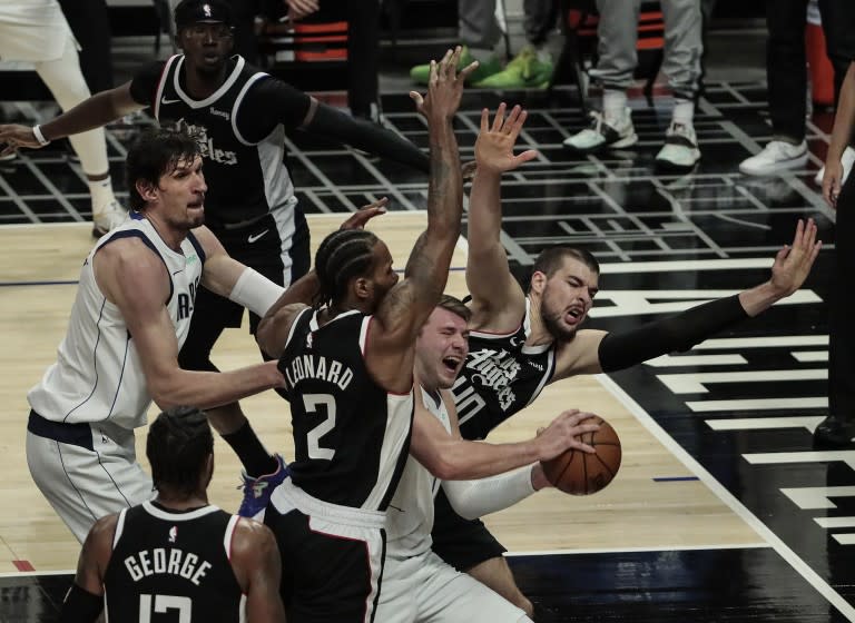 Mavericks guard Luka Doncic is surrounded by Clippers defenders on a drive down the lane.