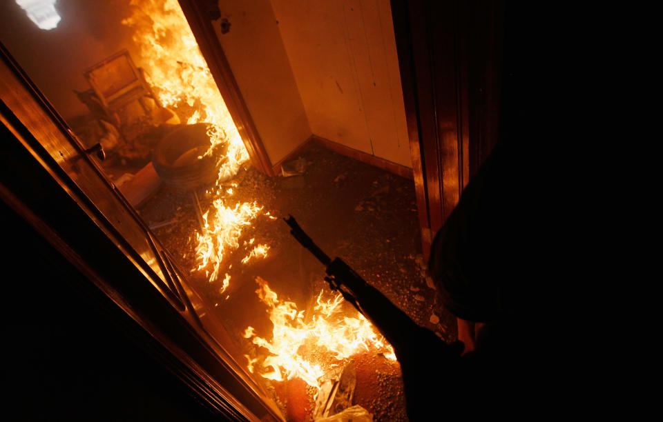 <p>A Libyan rebel fighter covers a burning room containing ensconced government loyalist troops who were firing on them during house-to-house fighting on Tripoli Street in downtown Misrata April 20, 2011 in Misrata, Libya. (Photo by Chris Hondros/Getty Images) </p>