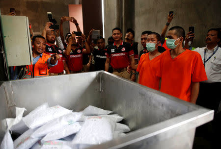 Drug suspects are brought in to watch as recently confiscated narcotics, including 1.4 tonnes methamphetamine and a large amount of ecstasy pills, are loaded into an incinerator by police following a ceremony by drug enforcement agencies in Jakarta, Indonesia August 15, 2017. REUTERS/Darren Whiteside