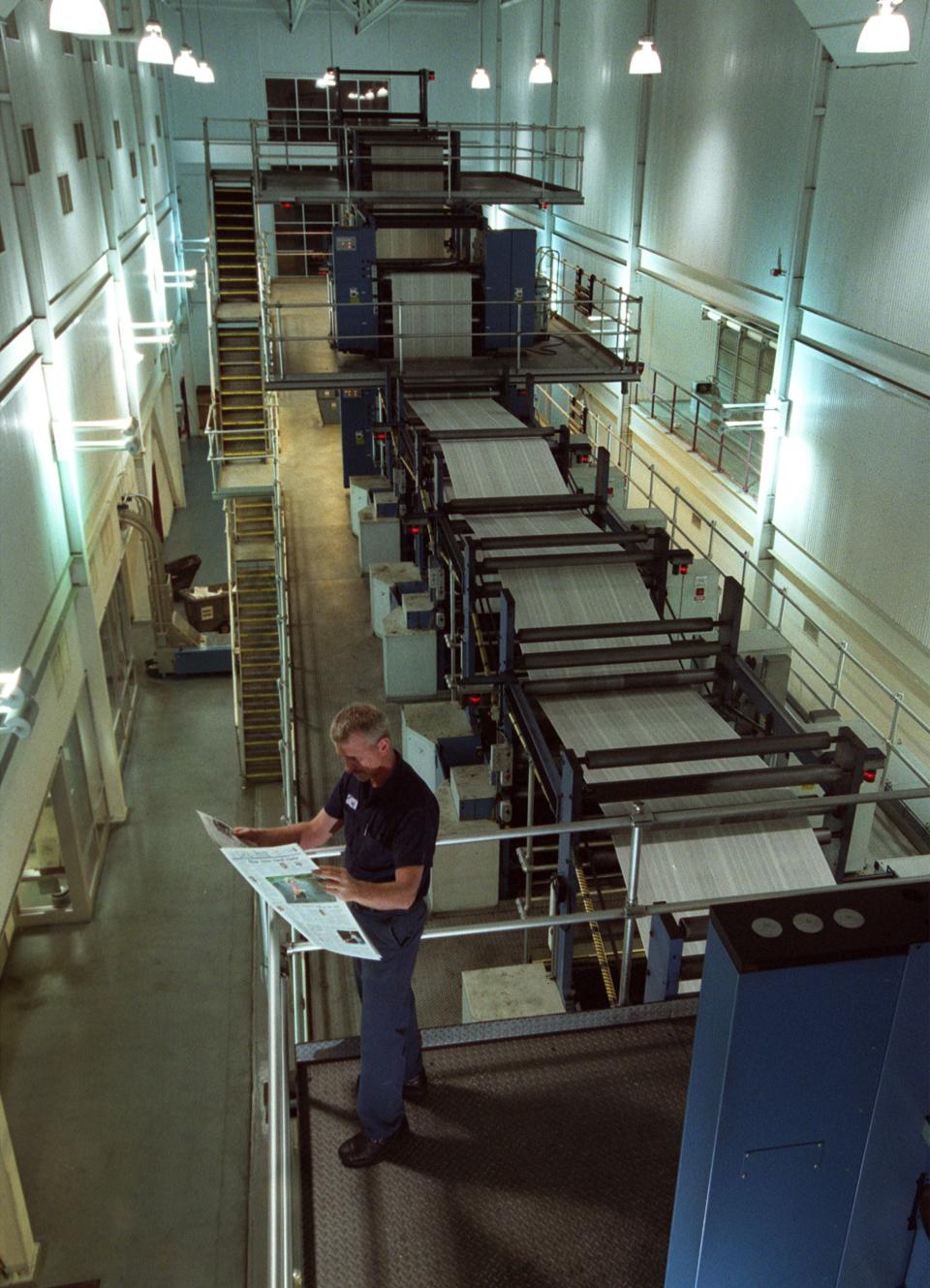 A press worker looks over a copy of The Fayetteville Observer as the printing press runs on Sept. 1, 2002. The press is shutting down on April 9, 2023.