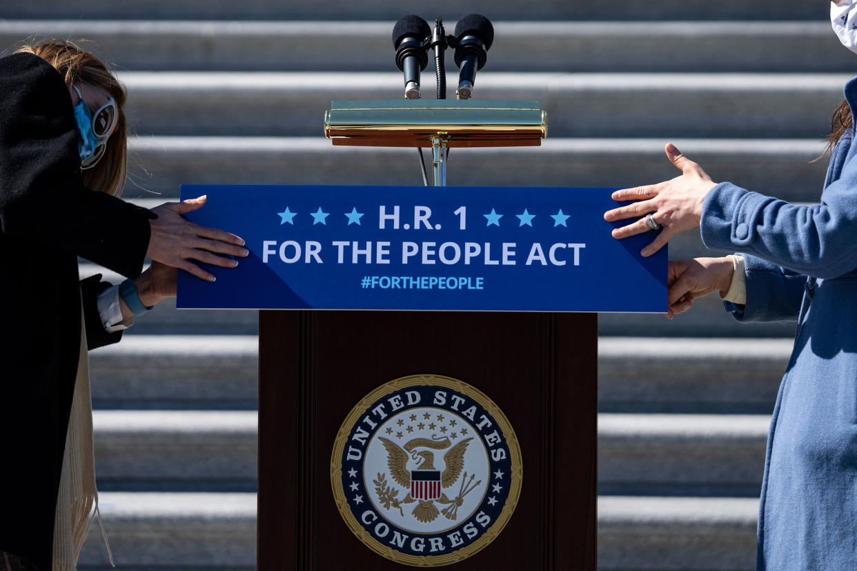 Staffers place a sign on a podium in preparation for a news conference with House Democrats regarding H.R. 1, the For the People Act, on Capitol Hill on March 3, 2021.