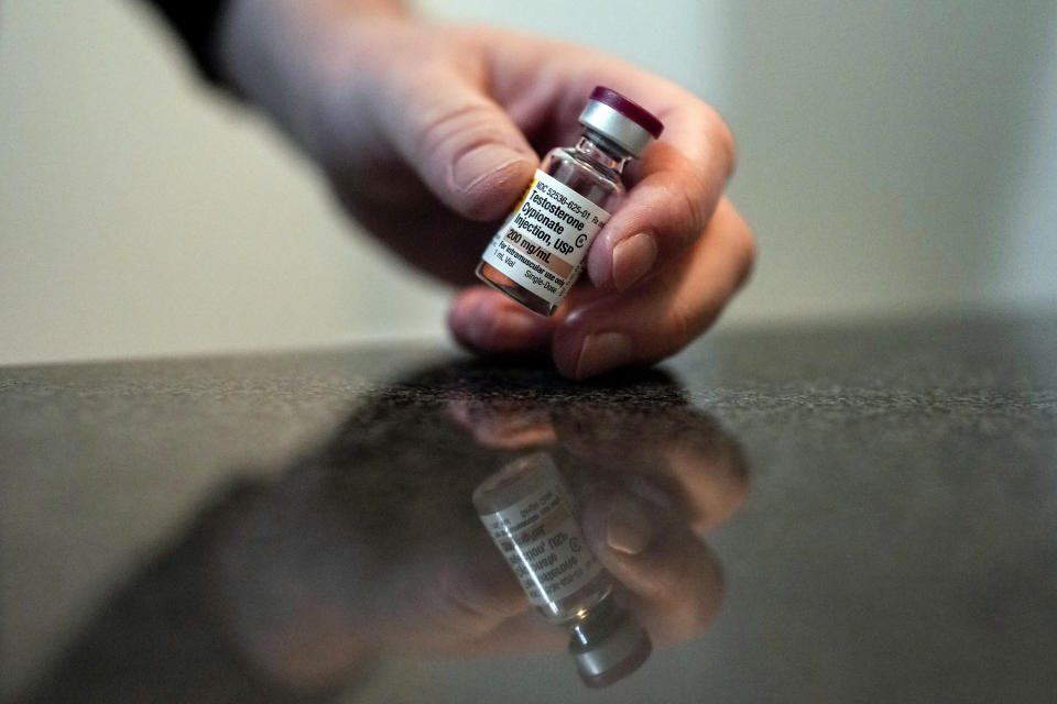 Ashton Colby holds a vial of Testosterone Cypionate Injection in his apartment bathroom in Columbus, Ohio, on Thursday, Jan. 18, 2024. Ohio Gov. Mike DeWine announced proposals this month that transgender advocates say could block access to gender-affirming care provided by independent clinics and general practitioners, leaving thousands of adults scrambling for treatment and facing health risks. Colby, 31, fears the clinic where he gets the testosterone he has taken since age 19 would no longer offer it. (AP Photo/Carolyn Kaster)