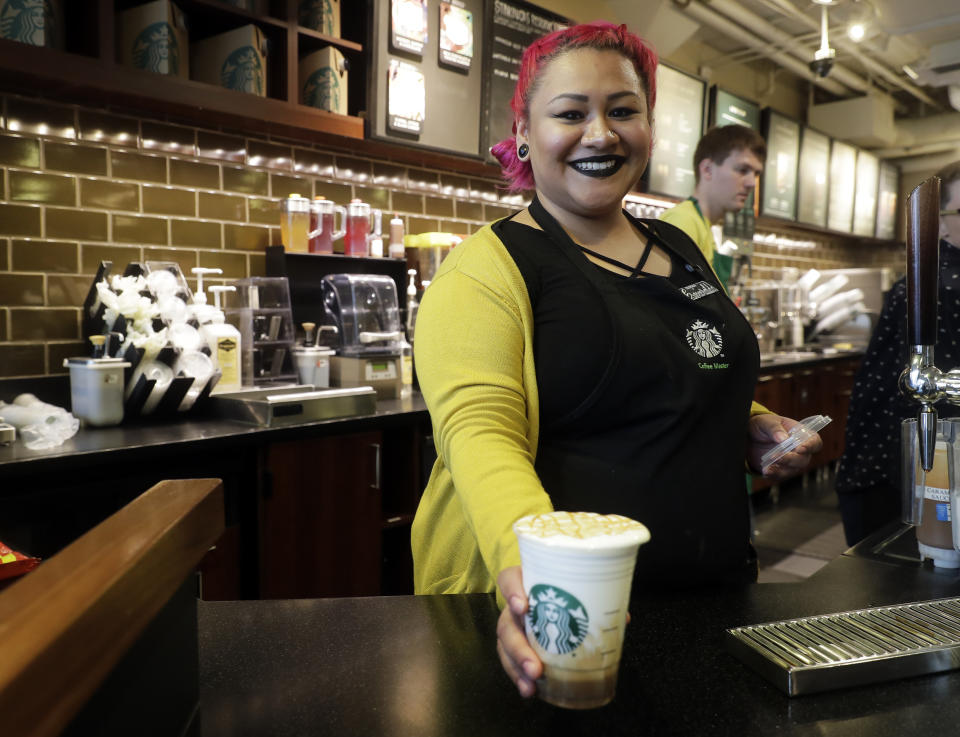 In this March 5, 2019, photo Esmeralda Chapparro, a Starbucks barista, moves a finished Cloud Macchiato coffee drink to the counter as she works at a store in the company's headquarters building in Seattle's SODO neighborhood. The new drink was introduced earlier in the month. (AP Photo/Ted S. Warren)