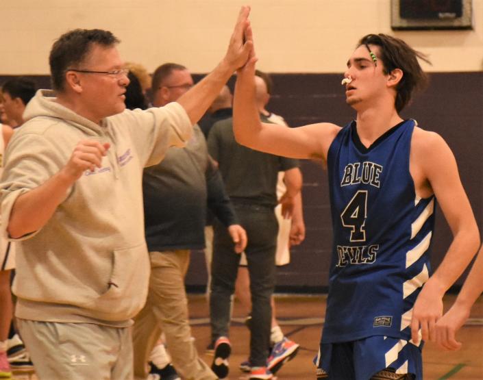 Dolgeville assistant coach Skip Gehring slaps hands with Blue Devil Michael Blaskey (right) after the horn signals the end of Thursday's season-opening victory over the Waterville Indians.