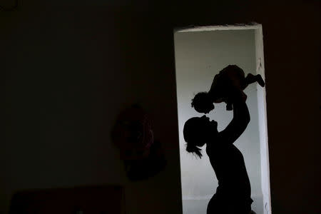 Rosana Vieira Alves holds her four-month-old daughter Luana Vieira, who was born with microcephaly, at their house in Olinda, Brazil, February 3, 2016. REUTERS/Ueslei Marcelino/File Photo