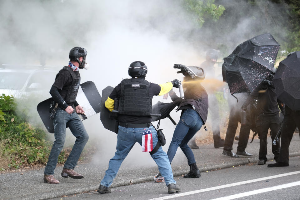 This Sunday, Aug. 22, 2021 photo, members of the far-right group Proud Boys and anti-fascist protesters spray bear mace at each other during clashes between the politically opposed groups in Portland, Ore. Police in Portland have been criticized that they did little to prevent violent clashes between right- and left-wing protesters on Sunday. (AP Photo/Alex Milan Tracy)