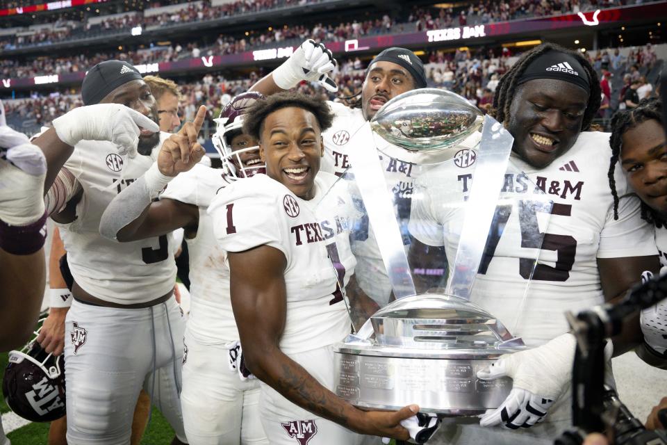 Sep 30, 2023; Arlington, Texas; Texas A&M Aggies wide receiver Evan Stewart (1) and offensive lineman Kam Dewberry (75) celebrate with the Southwest Classic trophy after the Aggies victory over the Arkansas Razorbacks at AT&T Stadium. Jerome Miron-USA TODAY Sports