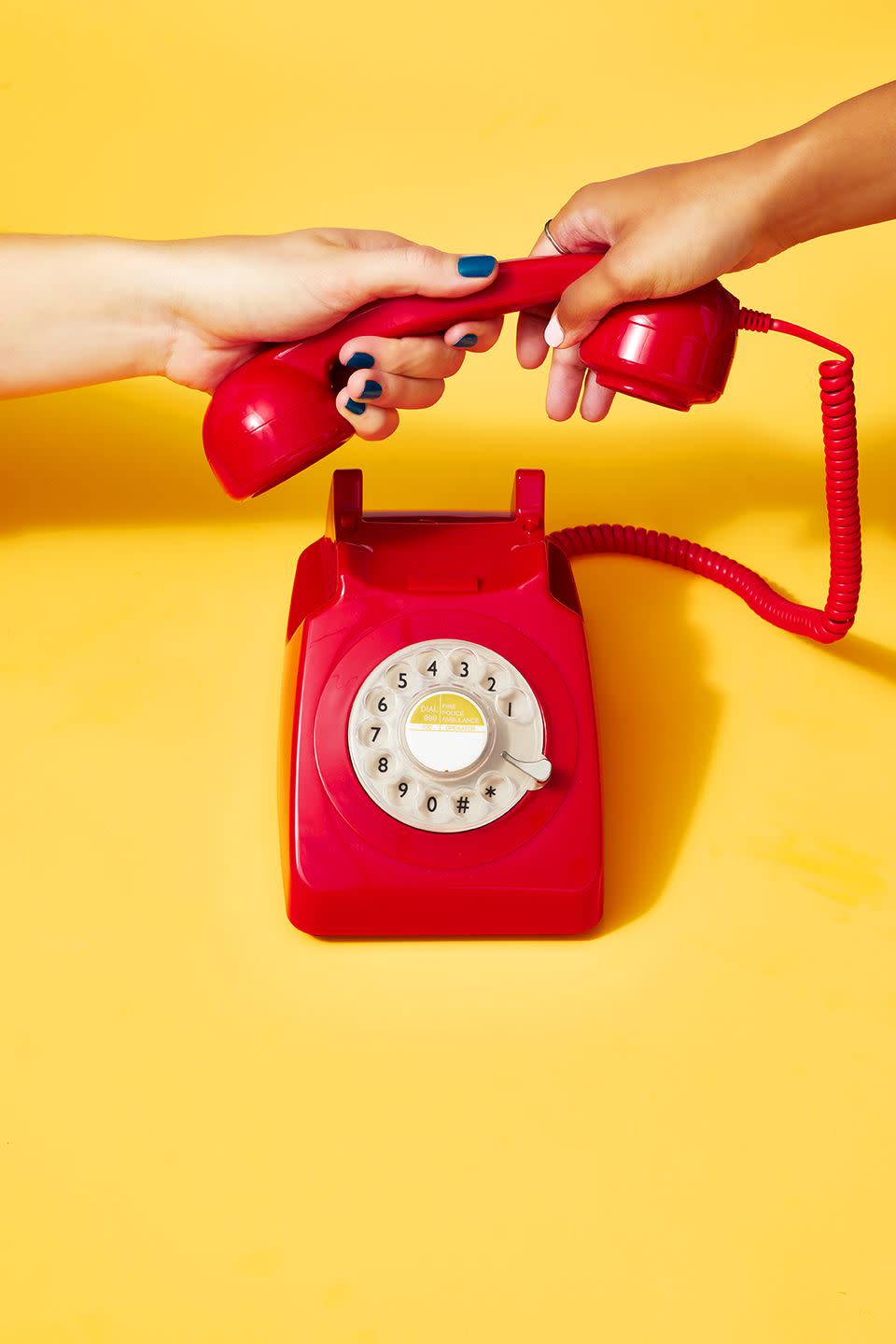 two female hands playing tug o war with a landline phone