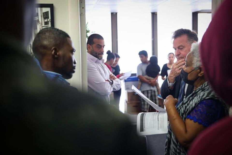 Randy McGrorty, cofundador de Catholic Legal Services, a la derecha, y Dámaso Ramírez, en el centro, intentan organizar a los inmigrantes que buscan ayuda dentro de los servicios legales de Catholic Charities el lunes 9 de enero de 2023, en el downtown de Miami.