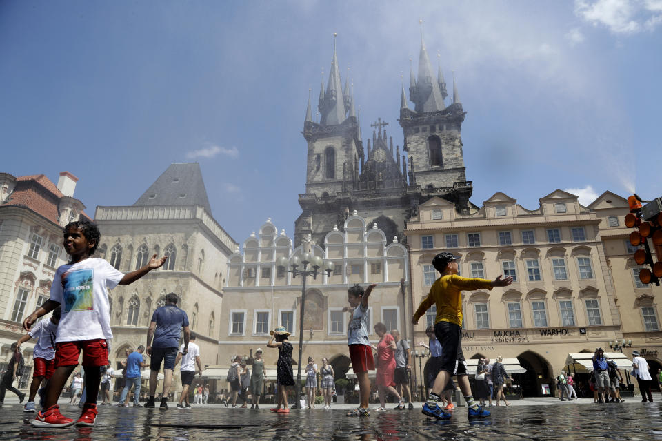 People cool down under the spray of water during a hot and sunny day at the Old Town Square in Prague, Czech Republic, Tuesday, June 25, 2019. (AP Photo/Petr David Josek)