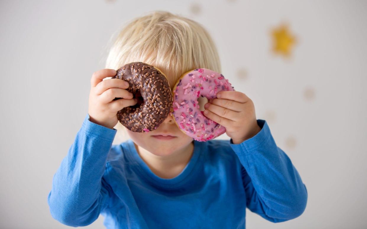 Child holding donuts up to his eyes - Alamy