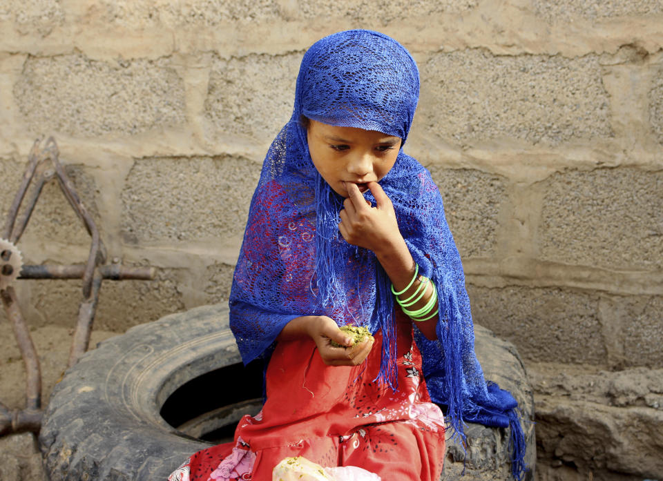 In this Aug. 25, 2018 photo, a girl eats boiled leaves from a local vine to stave off starvation, in the extremely impoverished district of Aslam, Hajjah, Yemen. The situation in Aslam district is a sign of the holes in an international aid system that is already overwhelmed but is the only thing standing between Yemen’s people and massive death from starvation amid the country’s 3-year civil war. (AP Photo/Hammadi Issa)