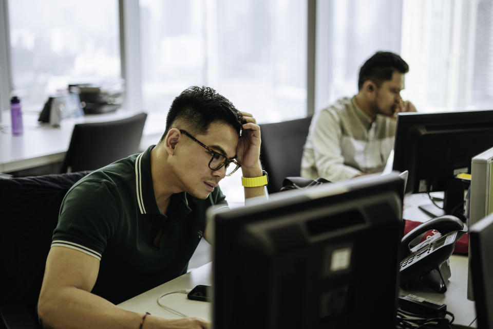 Two men are sitting in front of their computers at the office