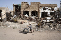 <p>Saada City, Yemen, April 23, 2017: A young boy runs with his tire past buildings damaged by airstrikes in Saada’s Old Town. Up until August 2015, this area was home to Saada’s oldest market with thousands of people selling vegetables, spices and fabrics in stores and street stalls. (Photograph by Giles Clarke for UN OCHA/Getty Images) </p>