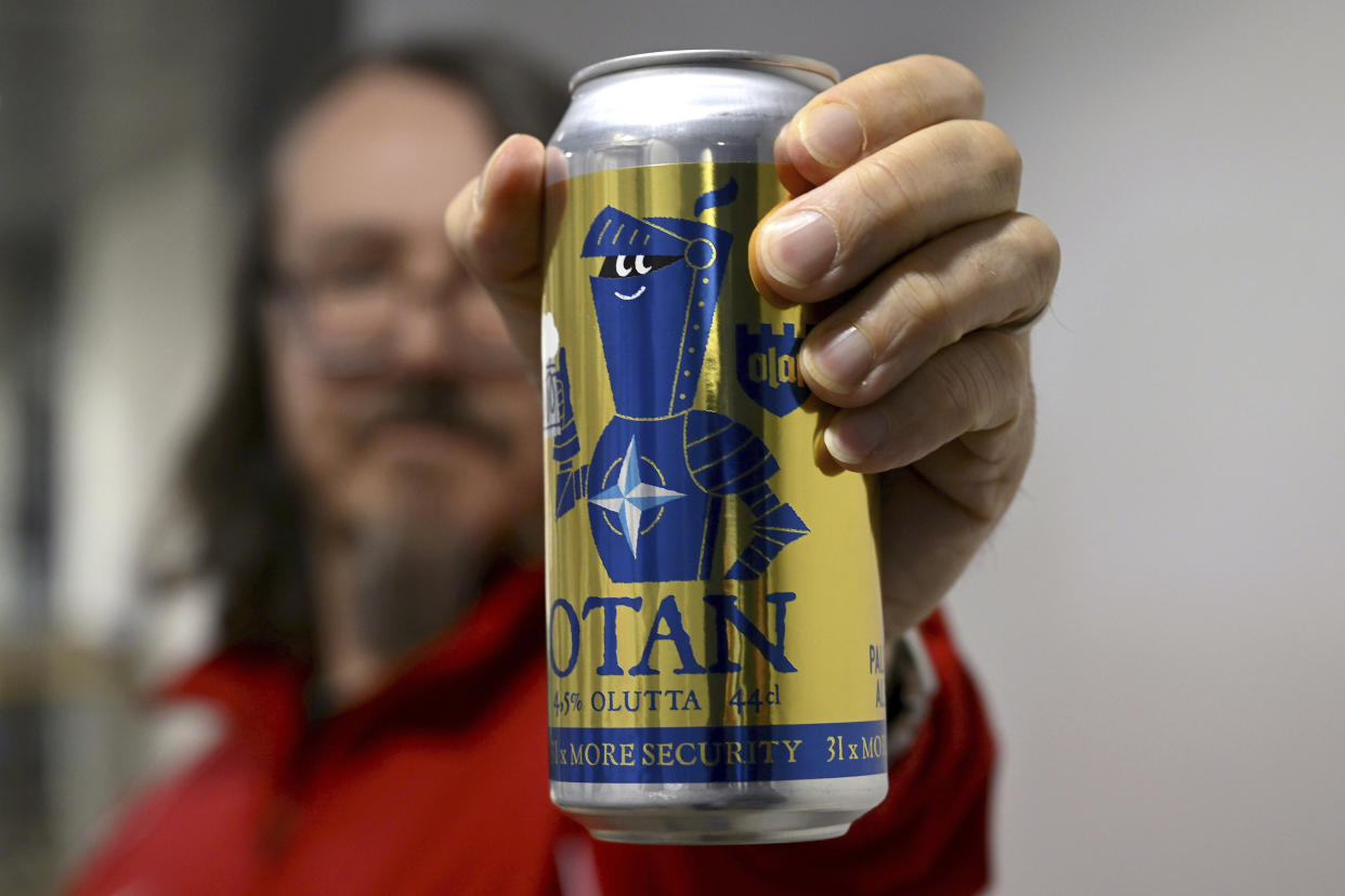 A man poses with a Nato-branded OTAN beer can (Gold Edition), in Helsinki, Finland on April 4, 2023. Finland is set to officially become a member of NATO later on Tuesday and take its place among the ranks of the world’s biggest security alliance. (Antti Aimo-Koivisto/Lehtikuva via AP)