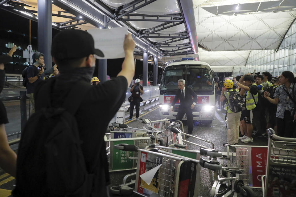 Protesters use luggage trolleys to block a police van during a demonstration at the Airport in Hong Kong, Tuesday, Aug. 13, 2019. Chaos has broken out at Hong Kong's airport as riot police moved into the terminal to confront protesters who shut down operations at the busy transport hub for two straight days. (AP Photo/Kin Cheung)