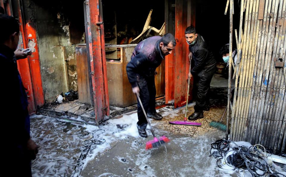 FILE - In this Wednesday, Feb. 5, 2014 file photo, Civilians clean up after a parked car bomb went off at a commercial center in Khilani Square in central Baghdad, Iraq. Car bombs are one of the deadliest weapons used by the al-Qaida breakaway group in Iraq that dominates the Sunni insurgency in Iraq, with coordinated waves of explosions regularly leaving scores dead in Baghdad and elsewhere across the country. (AP Photo/Karim Kadim)