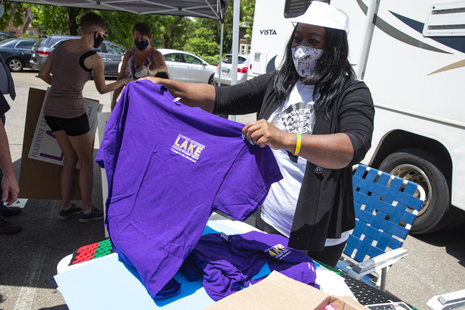 In this Friday, June 19, 2020, photo Jeannine Lee Lake, Democratic candidate for Indiana's 6th congressional district, passes out T-shirts during a Juneteenth day event in Columbus, Ind. Lake never would have imagined when she first ran against Greg Pence, Vice President Mike Pence's brother, for a rural Indiana congressional seat two years ago: An almost entirely white crowd of more than 100 people marching silently in the Pences' hometown, sending up prayers for Black people killed by police and an end to systemic racism. Leading them was Lake, who has launched a rematch against Pence. She is the only Black woman running for federal office in Indiana this fall. (AP Photo/Michael Conroy)
