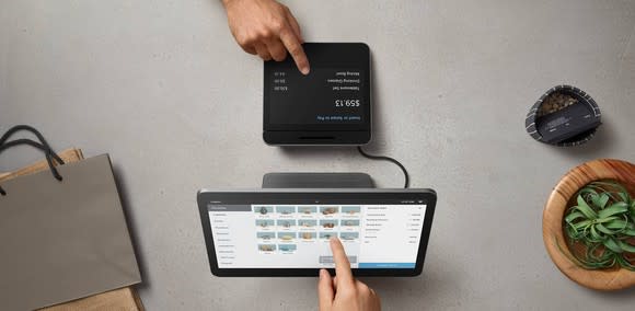 An employee and customer interact with the two displays included with Square Register.