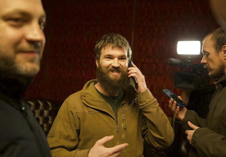 In this photo provided by the Ukrainian Interior Ministry Press Office, Azov officer Sviatoslav Palamar, center, who was released in a prisoner exchange between Russia and Ukraine, speaks on the phone in Ankara, Turkey, late Wednesday, Sept. 21, 2022. (Ukrainian Interior Ministry Press Office via AP)