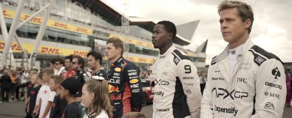 men in racing uniforms line up on track in f1