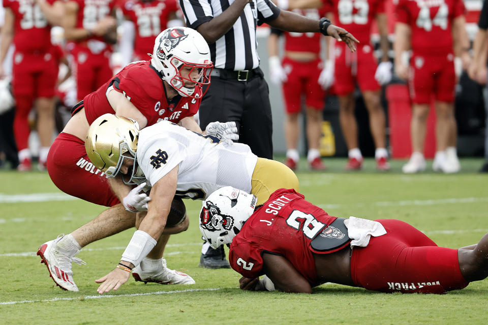 Notre Dame's Sam Hartman (10) is tackled by North Carolina State's Jaylon Scott, right, and Payton Wilson, left, during the first half of an NCAA college football game in Raleigh, N.C., Saturday, Sept. 9, 2023. (AP Photo/Karl B DeBlaker)