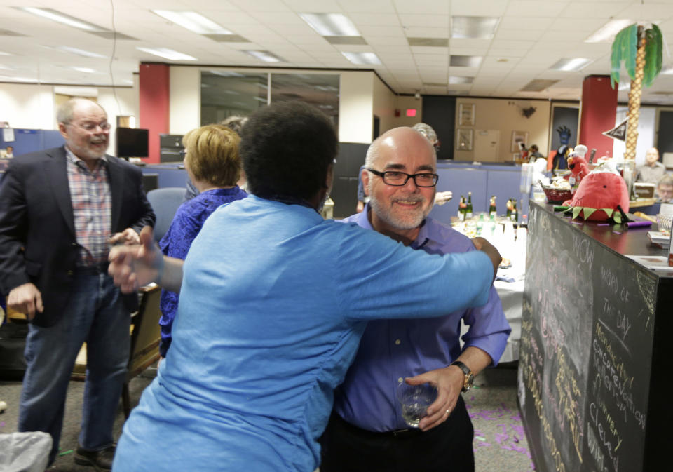 Charlotte Observer editorial cartoonist Kevin Siers, right, gets a hug from a co-worker as the newsroom celebrates Siers winning the Pulitzer Prize for Editorial Cartooning at the newspaper in Charlotte, N.C., Monday, April 14, 2014. (AP Photo/Chuck Burton)