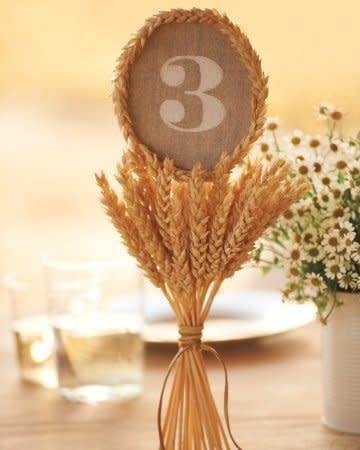 Set atop a bundle of wheat, large numerals direct diners to their tables. Linen-covered rounds of cardboard were stenciled with white paint, then placed on a stack of wheat -- the cut ends of which conveniently stand on their own.